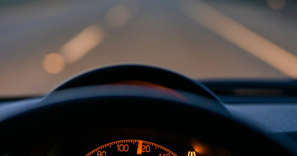Verlicht dashboard van een auto op de snelweg in de schemering