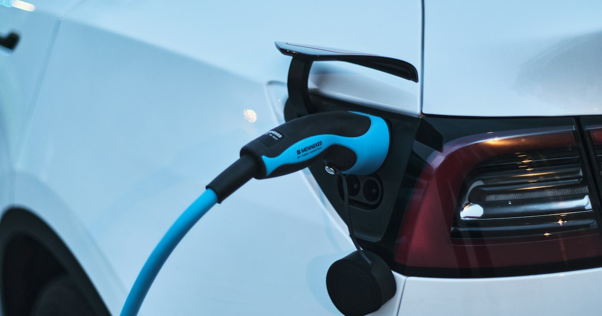 Witte elektrische auto die bij een laadpaal wordt opgeladen